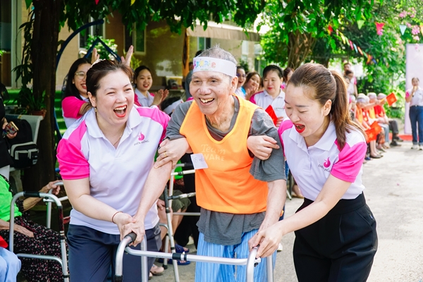 hai người phụ nữ đang dắt tay cụ ông để chạy tiếp sức