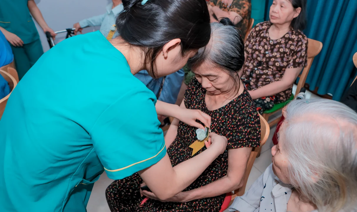 Điều dưỡng Diên Hồng cài bông hoa hồng trắng lên ngực áo các cụ